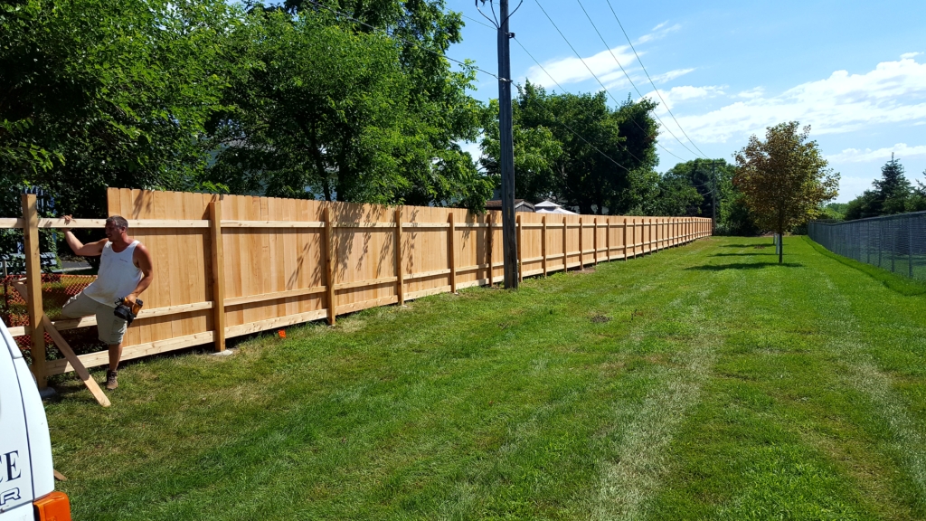 Premier Fence installer is building a cedar privacy fence a Summer day